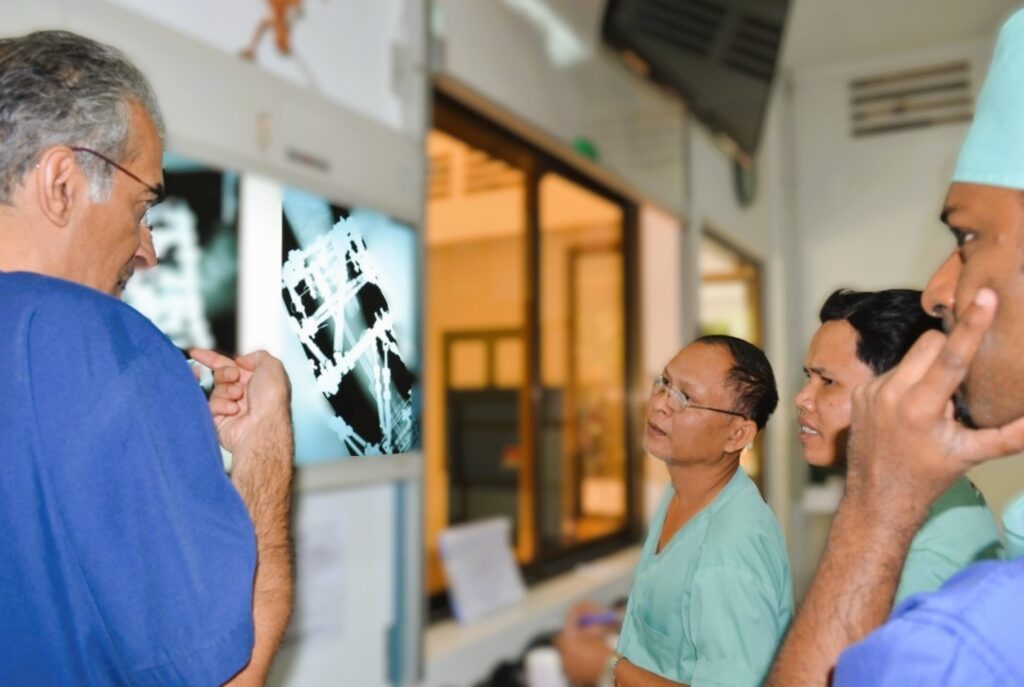 four orthopaediic healthcare workers discussing an ilizarov frame x-ray